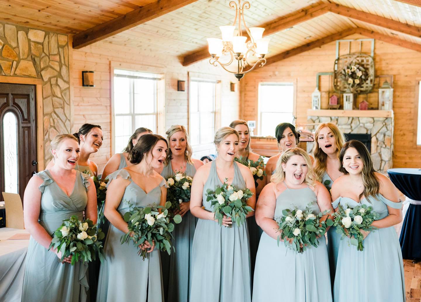 bridesmaids in baby blue dresses smiling at first look of the bride