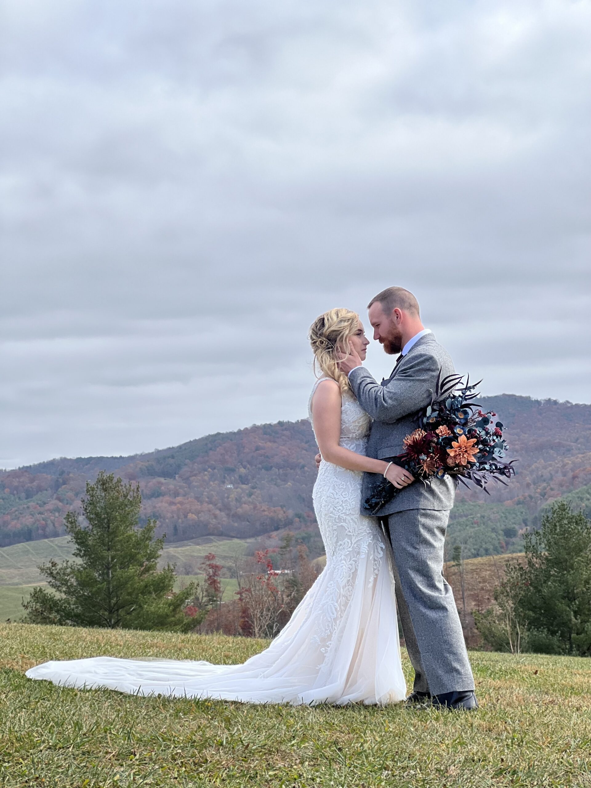Bride and groom embracing outdoors with scenic landscaspe beyond