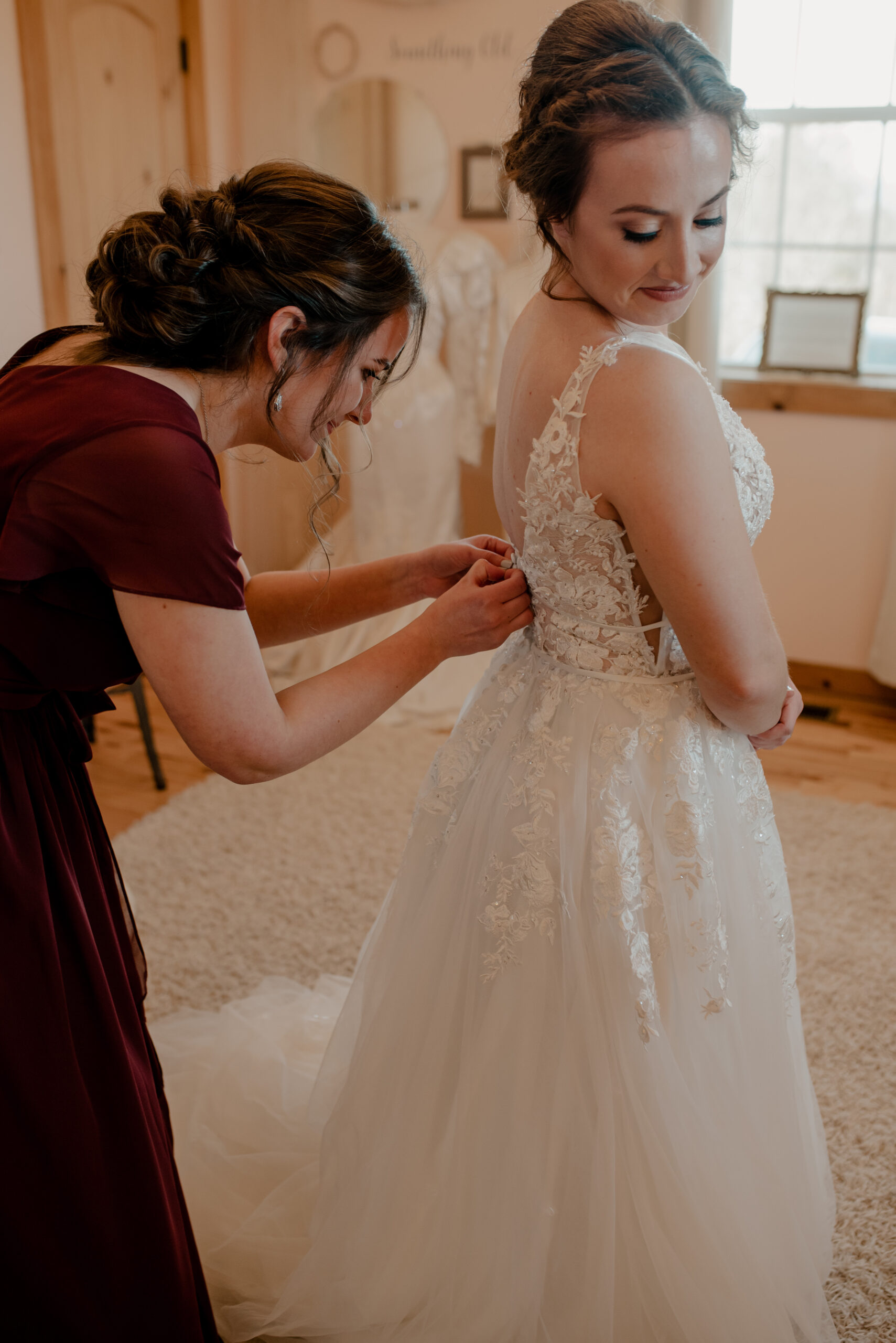 bride getting dress button with the help of a bridesmaid